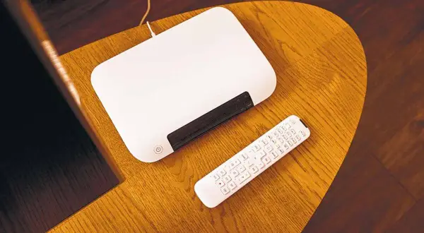Biały router i pilot na drewnianym stoliku. Dowiedz się, jak zmienić hasło w routerze T-Mobile.