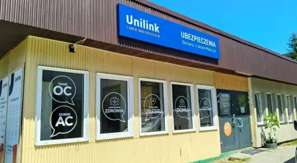 Budynek agencji ubezpieczeniowej Unilink z widocznymi na szybach hasłami: "Tanie OC", "Dobre AC", "Ubezpieczenie Zdrowia", "Na życie", "Domu".