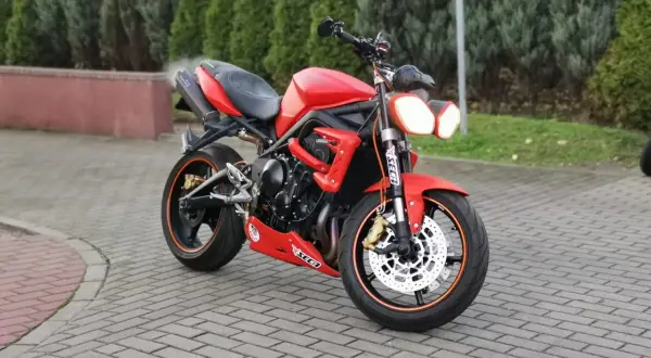Czerwony motocykl Triumph Street Triple 675 na brukowanym podjeździe.