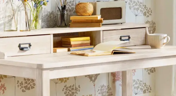 Scrivania chiara con cassetti, libri, tazza e radio vintage. Ideale per chi vuole imparare come verniciare un mobile da marrone a bianco.