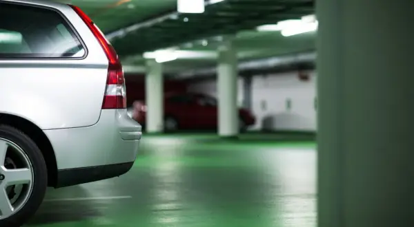 Voiture argentée dans un parking souterrain. Le sol est vert vif. On dirait que le propriétaire prépare une lettre préavis garage 1 mois.