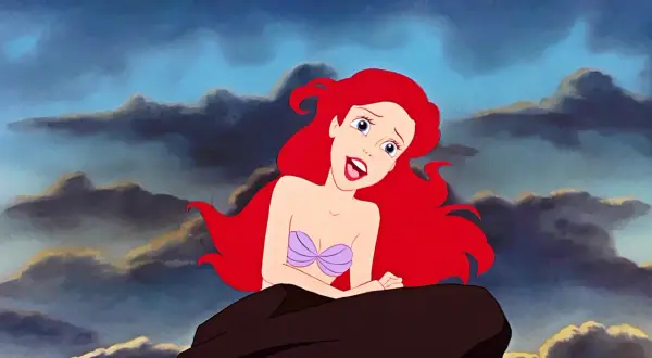 Ariel z "Małej Syrenki" na skale, z burzowymi chmurami w tle. W jej oczach widać marzenie o śpiewaniu w świecie ludzi, jak w pięknych **disney piosenki**.