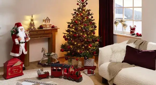 En julgran med röda kulor och ljus ger inspiration till en mysig jul. Tomten, leksakståg och en gungande häst skapar en festlig stämning.
