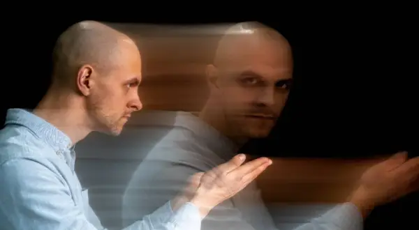 Uomo calvo con effetto mosso, sembra diviso tra due stati, un'immagine che evoca un disturbo del controllo.