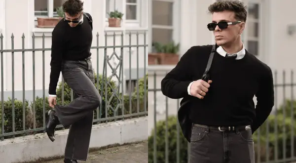Mann in schwarzem Pullover, weißem Hemd und dunkler Hose, bereit für ein Techno-Festival. Coole Sonnenbrille und Stiefel runden den Look ab.