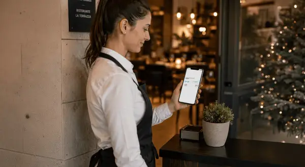Cameriera controlla il telefono al ristorante "La Terrazza". Anche se sabato è un giorno feriale, il locale è pronto per accogliere i clienti.