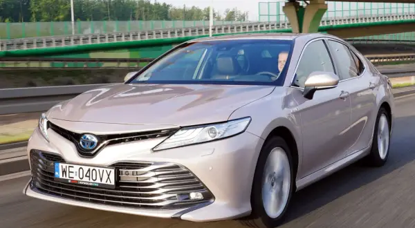 Elegancka Toyota Camry Hybrid w kolorze szampańskim na drodze. Sprawdź atrakcyjną toyota camry cena.