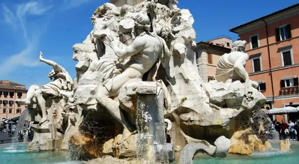 La Fontana dei Quattro Fiumi di Bernini, con le sue maestose statue che rappresentano i fiumi del mondo, zampilla sotto il cielo azzurro di Roma.