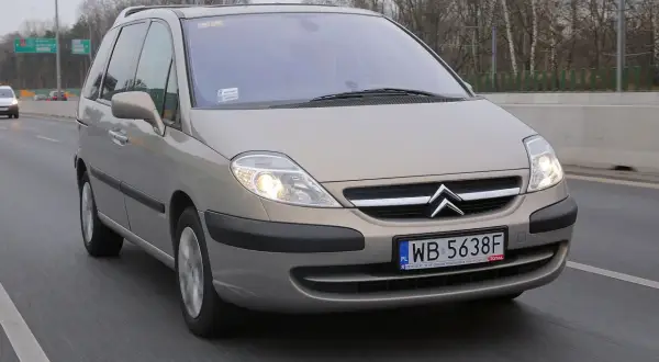 Złoty Citroën C8 na drodze, światła włączone, tablica rejestracyjna WB 5638F.