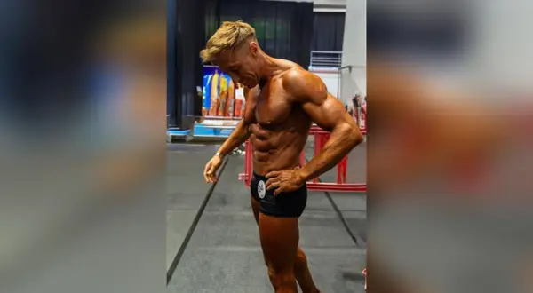 Ein Mann mit beeindruckendem **men's physique** posiert, seine Muskeln sind definiert und gebräunt.