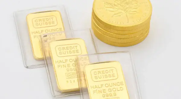 Sztabki złota Credit Suisse i stos kanadyjskich monet z liściem klonu, symbolizujące inwestycje w złoto LBMA.