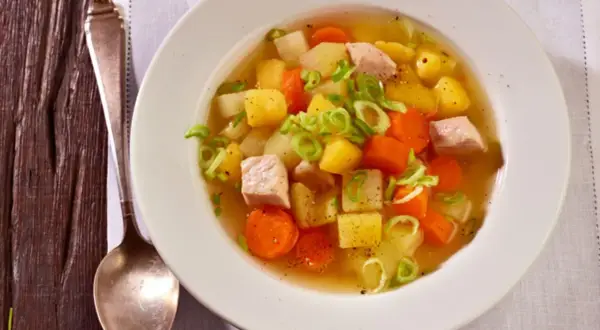 Herzhafter Kohlrabi-Eintopf mit Fleischwürfeln, Kartoffeln und Karotten, garniert mit Frühlingszwiebeln.