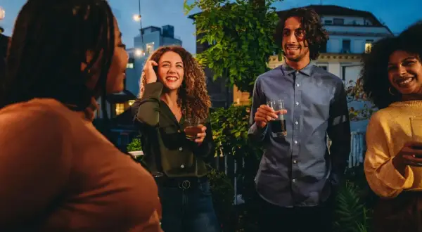 Vänner samlas på en takfest i Berlin, med ljusslingor och stadens silhuett i bakgrunden. En kväll fylld av skratt och goda drinkar, som en liten bit av fakta om Berlin.