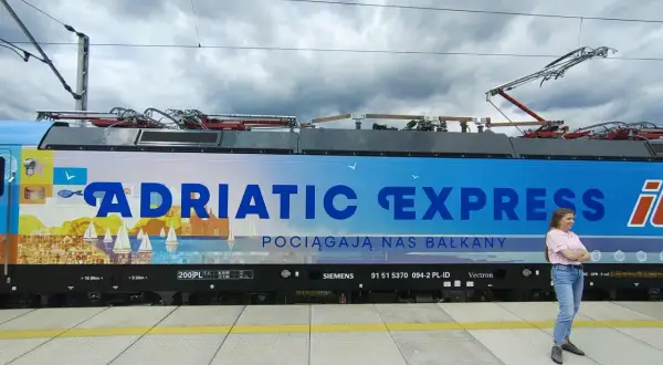 Kobieta na tle lokomotywy "Adriatic Express", która zabierze ją pociągiem do Chorwacji.