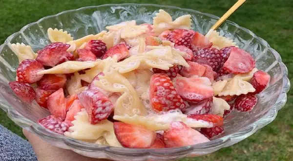 Makaron farfalle z kawałkami świeżych truskawek, polany kremowym sosem. Letnia uczta w misce.
