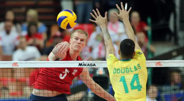 Kyle Russell z USA atakuje piłkę do siatkówki, blokowany przez Douglasa z Brazylii.
