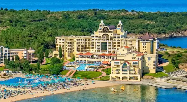 Duni Royal Pelican: luksusowy hotel z basenami i plażą nad morzem, otoczony zielenią.