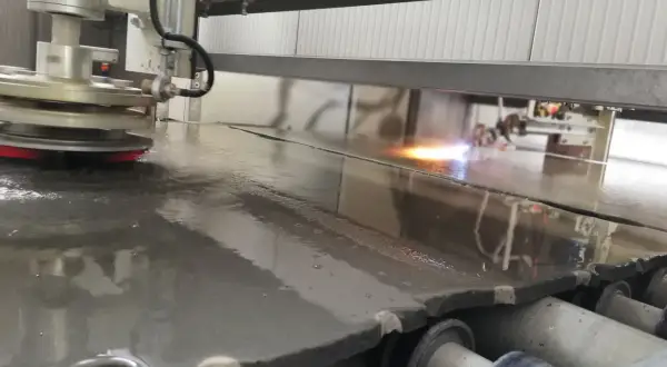 Macchina industriale esegue la fiammatura marmo, creando una superficie ruvida e antiscivolo.