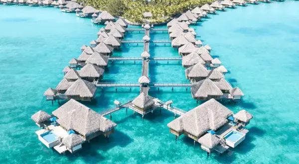 Bora Bora, gdzie jest ten raj? Domy na wodzie z krytymi strzechą dachami w turkusowej lagunie.