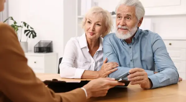 Un couple âgé discute d'une procuration pour leur compte bancaire avec un conseiller.