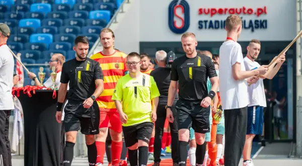 Piłkarze i sędziowie wchodzą na murawę stadionu.
