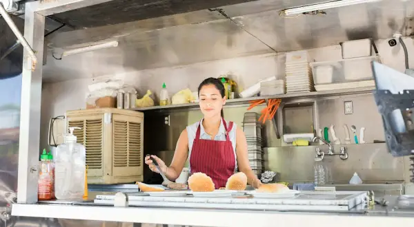 Donna prepara panini nel suo food truck, un sogno che sta per aprire.