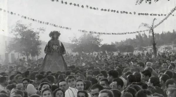 Una figura alta, vestida con traje tradicional, se alza sobre una multitud. Es parte de la **historia del Rocío**, una tradición ancestral.
