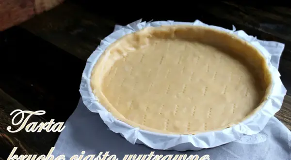 Surowe ciasto kruche wytrawne na tartę, przygotowane do pieczenia. Widelcem nakłute dno i boki.