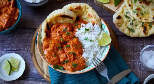 Ein köstliches Butter Chicken Rezept mit Reis, Naan und Limettenspalten. Perfekt für ein authentisches indisches Essen.