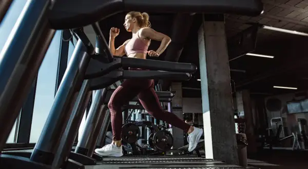 Mujer corriendo en una cinta de correr en un gimnasio moderno.
