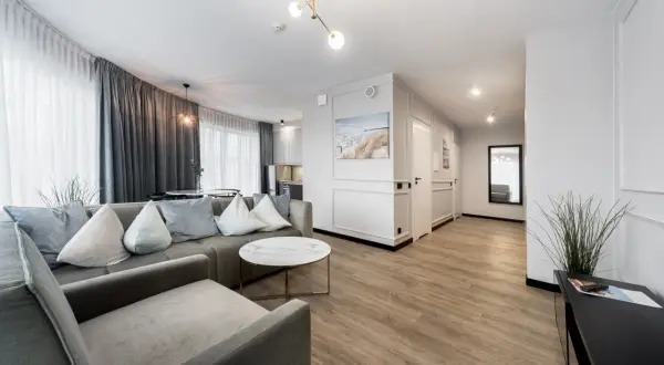 Nowoczesny apartament z szarą sofą, okrągłym stolikiem i widokiem na kuchnię.