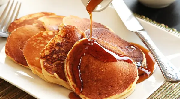 Pancakes dorati, preparati con bicarbonato al posto del lievito, vengono irrorati da uno sciroppo ambrato.