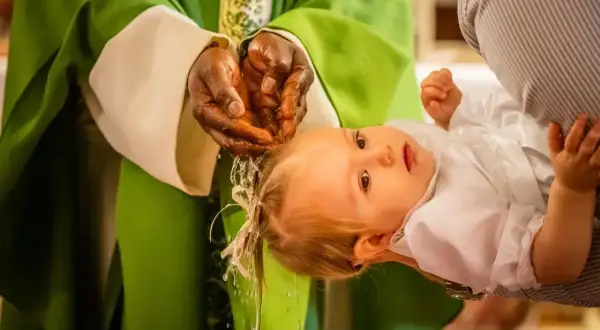 Un bébé est baptisé, de l'eau coule sur sa tête. Une étape importante, le baptême civil, une démarche pour la vie.