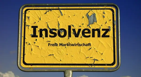 Gelbes, verwittertes Ortsschild mit der Aufschrift "Insolvenz" und "Freie Marktwirtschaft". Es fragt: was ist Insolvenz?