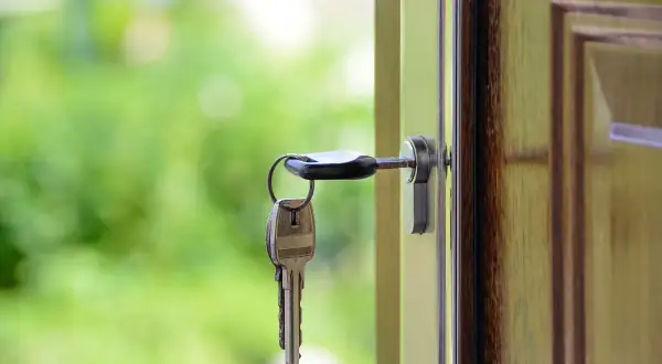 Llaves colgando de una puerta abierta, simbolizando el intercambio de casas entre particulares.