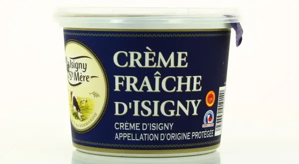 Un pot de crème fraîche d'Isigny, avec une vache dans un pré sur l'étiquette. La crème d'Isigny est une spécialité normande.