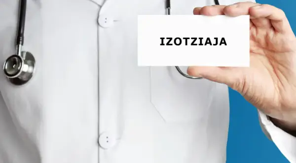 Lekarz w białym kitlu trzyma kartkę z napisem "IZOTZIAJA". Stetoskop wisi na jego szyi.
