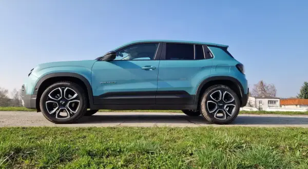 Turkusowy Jeep Avenger na tle błękitnego nieba. Z boku widoczna nazwa modelu i felgi. Idealne wymiary dla miejskiego SUV-a.