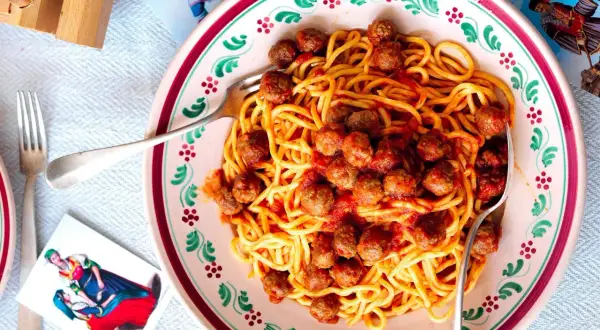 Spaghetti alla chitarra con polpettine in un piatto decorato, pronti per essere gustati.