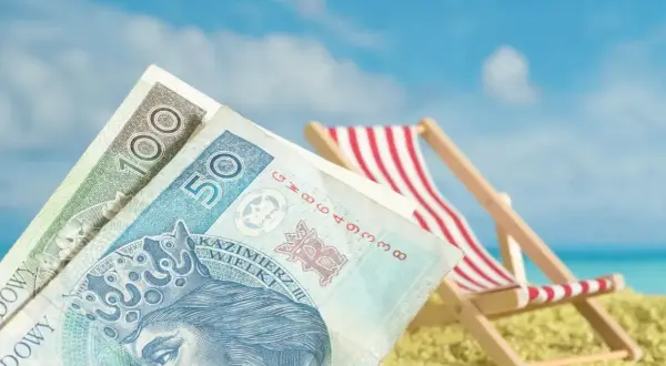 Pieniądze na plaży, leżak i błękitne niebo. Czy niewypłacanie świadczenia urlopowego co to znaczy?