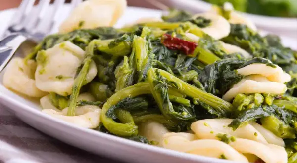 Piatto di orecchiette cime di rapa, un classico della cucina pugliese, con verdure verdi e un tocco di peperoncino.