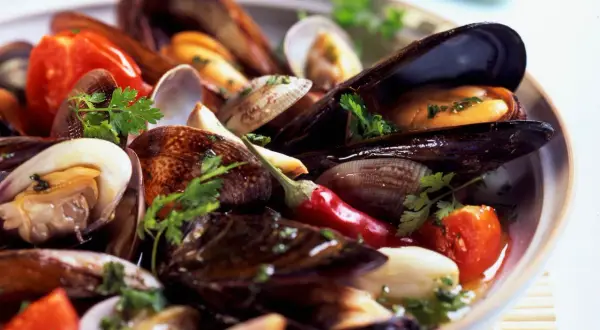 Un invitante sugo cozze e vongole, con pomodorini, peperoncino e prezzemolo fresco, pronto per essere gustato.
