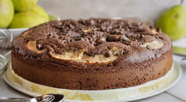 Torta pere e cioccolato, soffice e golosa, con tante gocce di cioccolato e fette di pera che spuntano dalla superficie.