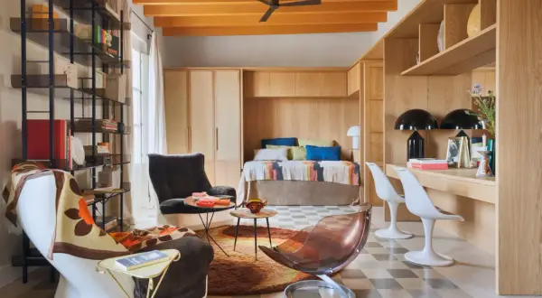 Un espacio acogedor que demuestra cómo los **mini apartamentos** pueden ser funcionales y estilosos, con cama empotrada, zona de trabajo y cómodos asientos.