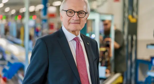 Gerteric Lindquist, en äldre man med glasögon och slips, står i en fabriksmiljö.