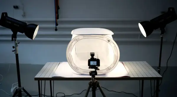 Studio do fotografii produktowej z aparatem na statywie, dyfuzorem i dwoma lampami tworzącymi światło kontrowe.