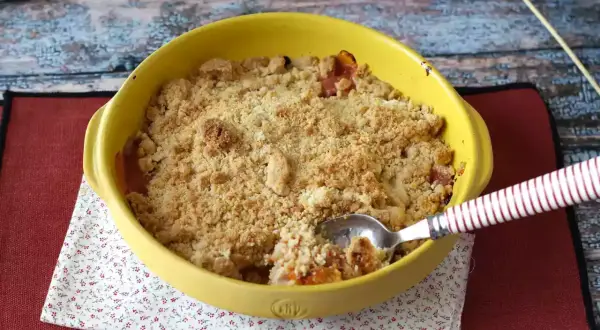Ein goldbrauner Aprikosen Crumble in einer gelben Auflaufform, bereit zum Genießen.