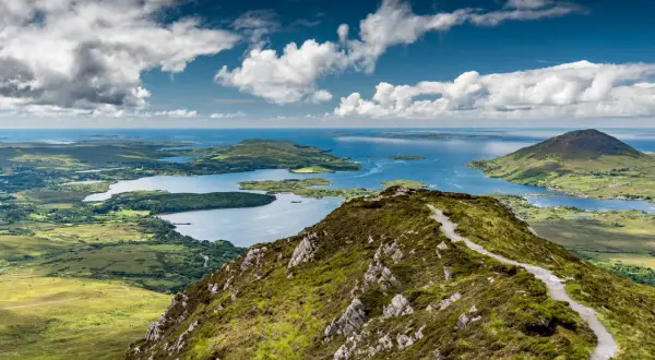 Sentier de randonnée Connemara, vue panoramique sur les lacs et les îles sous un ciel nuageux.