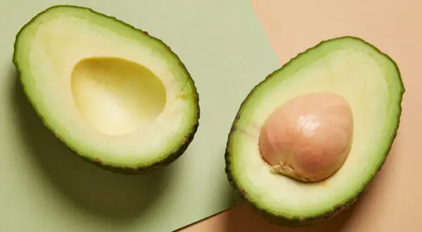 Deux moitiés d'avocat, l'une sans noyau, l'autre avec son noyau. Un aliment sain, mais attention à la prise de poids si consommé en excès.