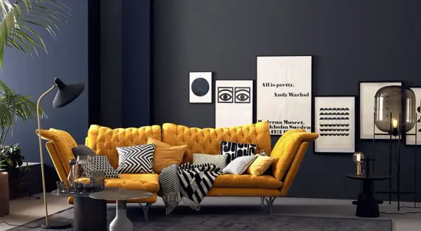 Ein senfgelbes Sofa kombiniert mit grafischen Kissen und einer dunklen Wand schafft einen modernen Look.